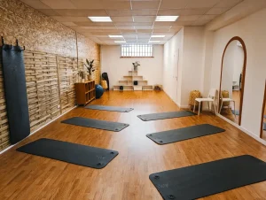 Salle de cours collectifs (par exemple Pilates) avec du parquet au sol, dans une ambiance chaleureuse