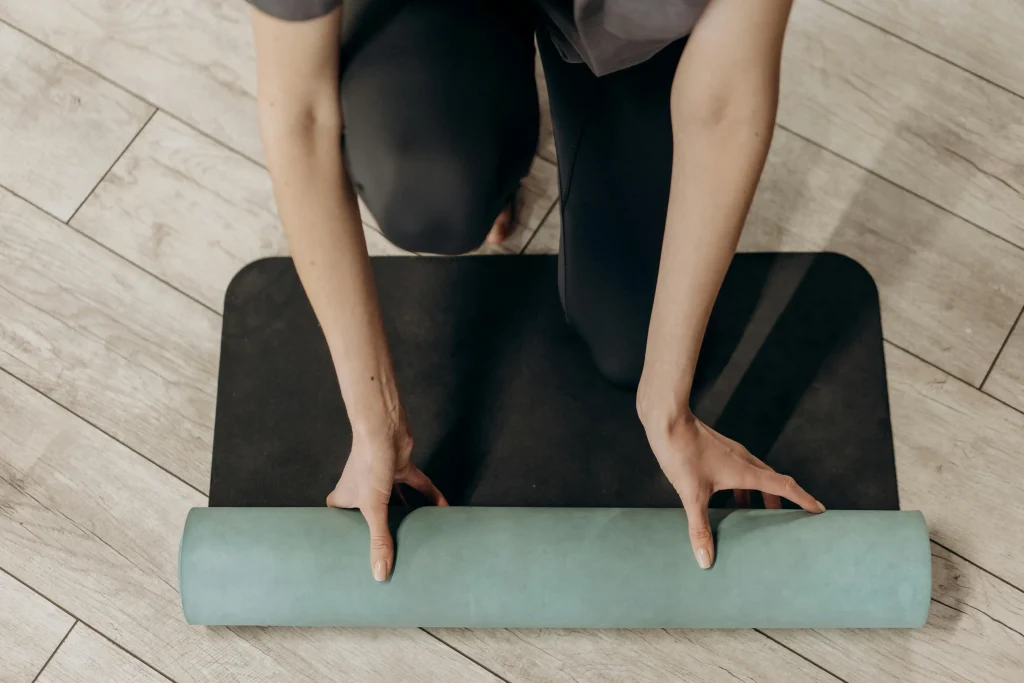 femme-roulant-tapis-yoga Une femme roule un tapis de yoga à la fin d'une séance