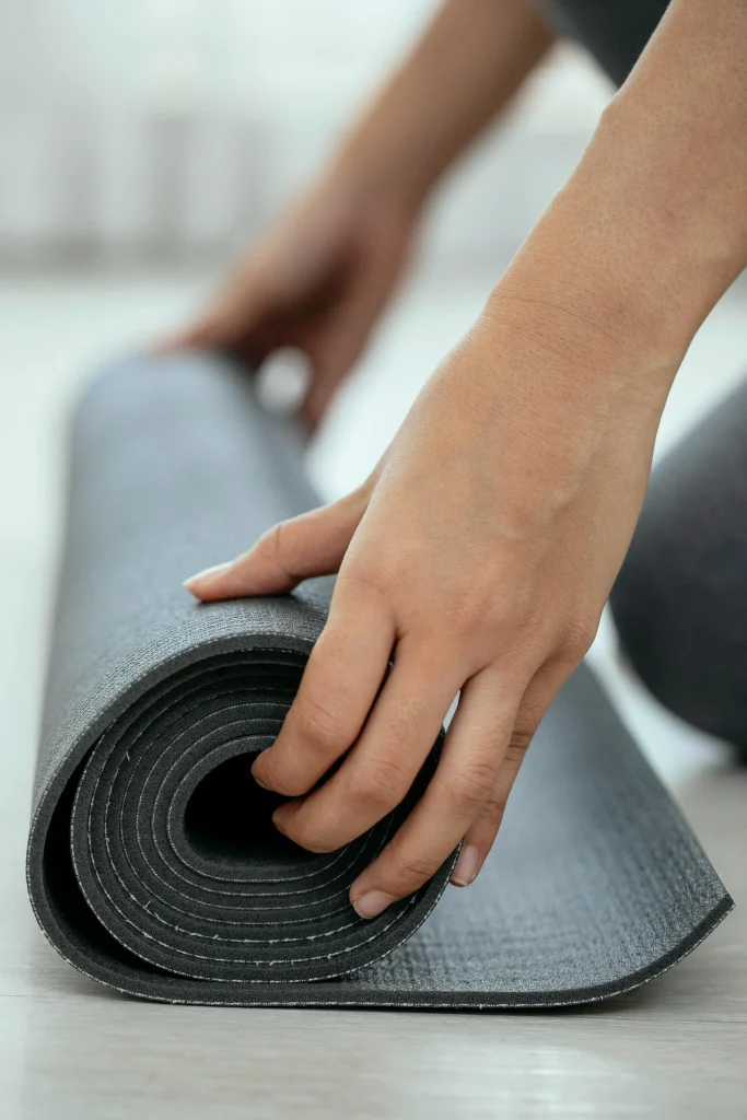 femme-roulant-tapis-yoga-cote Une femme roule un tapis de yoga. La prise de vue est au niveau du sol