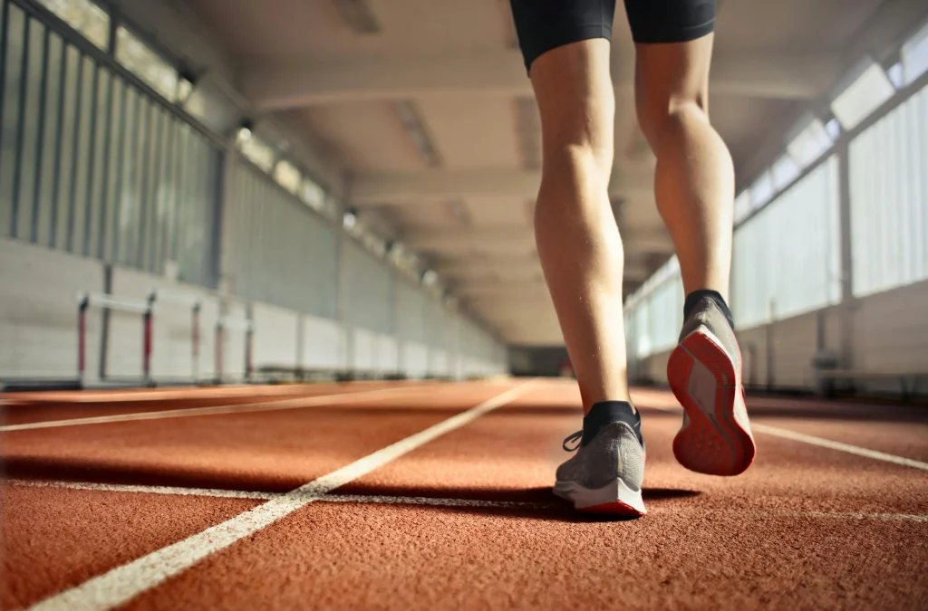 joggin-sur-piste-athletisme Un coureur s'échauffe à faible allure sur une piste d'athlétisme indoor.