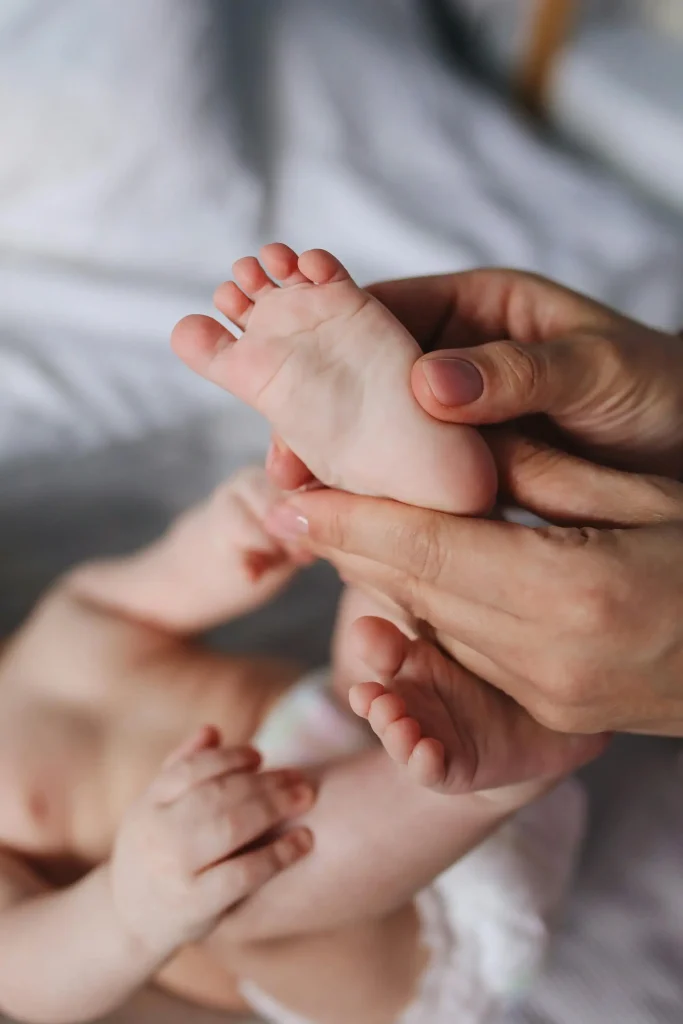 Une ostéopathe prodigue un massage bébé sur les pieds d'un nourisson