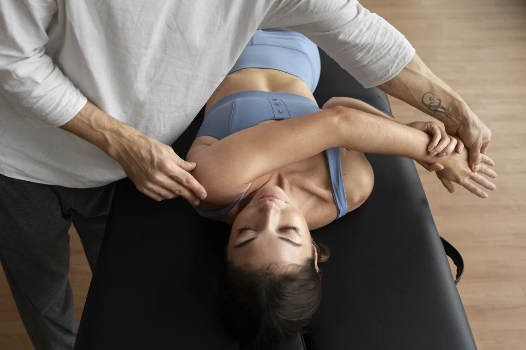 osteopathe-technique-epaule Un ostéopathe réalise une manipulation structurelle au niveau de l'épaule d'une patiente allongée.