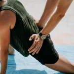 Rééducation du sportif : un kinésithérapeute accompagne un patient pour effectuer un étirement de son bas du dos et du psoas