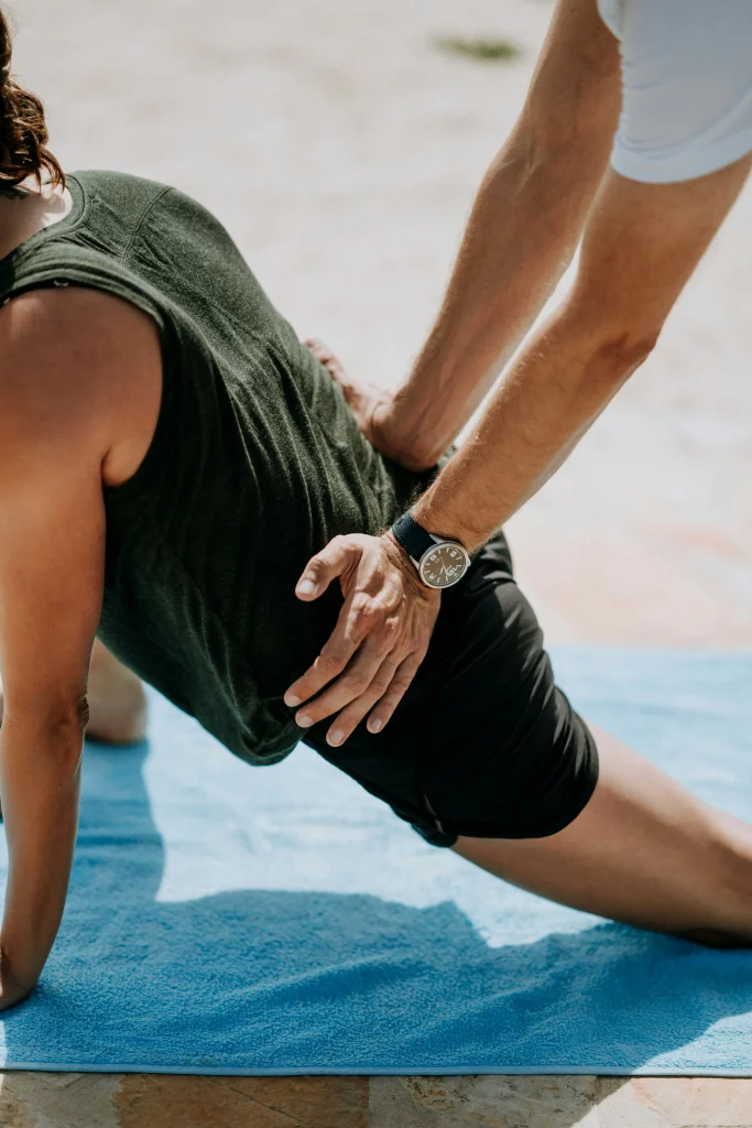 Un kiné du sport accompagne un patient sportif pour effectuer un étirement de son bas du dos et du psoas