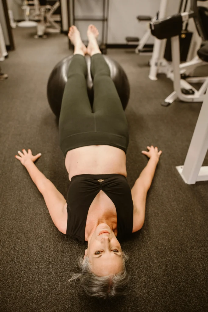 Une dame âgée réalise des exercices de type planche sur un ballon de fitness pour renforcer son périnée.